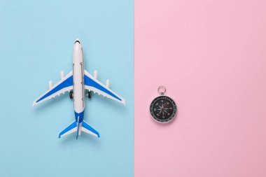 Model airplane with compass on pink blue background. Travel concept. Flat lay, top view