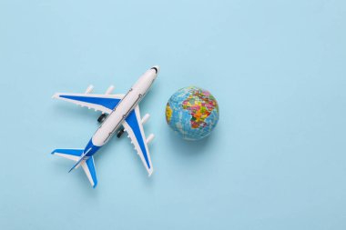 Toy model airplane with globe on blue background. Travel concept. Flat lay, top view