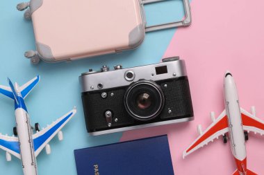 Kamera, mavi arka planda bavulu ve pasaportu olan yolcu uçakları. Seyahat konsepti. Düz yatış, üst görünüm