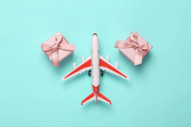 Toy Passenger plane with gift boxes on blue background. Top view. Flat lay