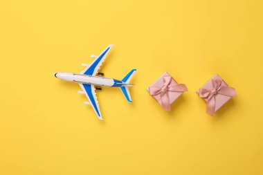 Toy Passenger plane with gift boxes on yellow background. Top view.