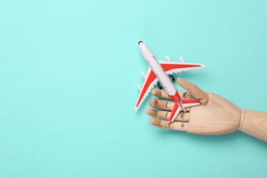 Ahşap El mavi arka planda Oyuncak Yolcu uçağını tutuyor. Üst Manzara. Düz yatıyordu