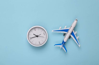 Mavi arka planda saati olan bir model uçak. Seyahat konsepti. Düz yatış, üst görünüm