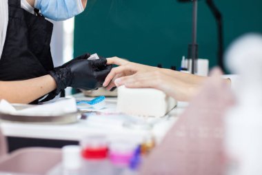 Manikürcü müşterinin tırnaklarıyla çalışıyor. Tırnak bakımı, manikür.