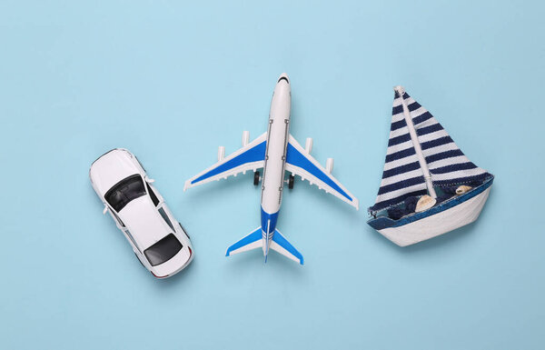 Toy Passenger plane, car and sailboat on blue background. Transport. Travel concept. Top view. Flat lay
