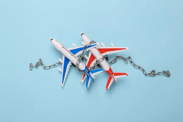 Air travel ban. Airplanes wrapped in chain and on blue background. Top view. Flat lay