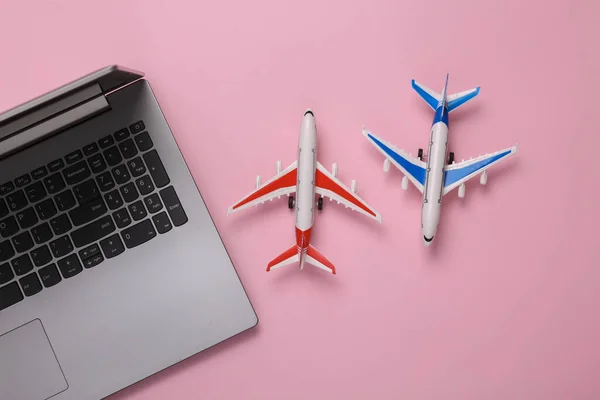 Model airplanes with laptop on pink background. Travel concept. Flat lay, top view