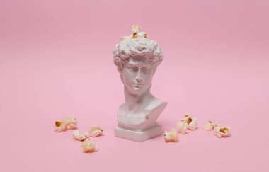 David bust with popcorn on pink background. Minimal still life. Concept art