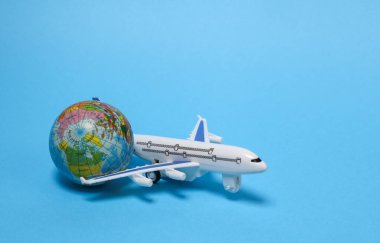 Voyage, Travel concept. Toy Airplane with a globe on blue background