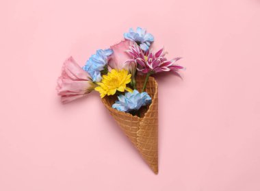 Romantic flat lay. Waffle cone with different flowers on pink background. Creative layout. Flat lay