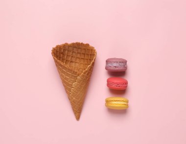 Minimal food still life. Waffle cone with French macaroons on a pink pastel background. flat lay 