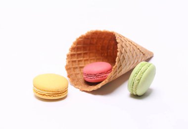 Minimal food still life. Waffle cone with French macaroons isolated on white background.