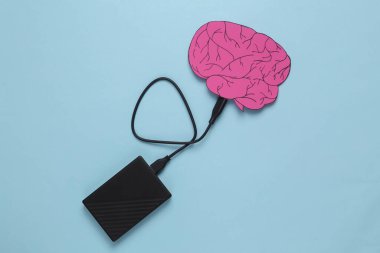 Paper-cut brain with external hard drive connected on a blue background. Futuristic technologies of digitalization of consciousness. Memory storage