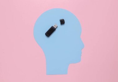 Paper-cut head with usb flash drive on a pink background. Storage of memories