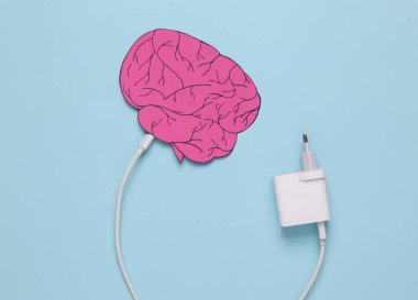 Recharge your brains. Paper-cut brain with a connected charger on a blue background