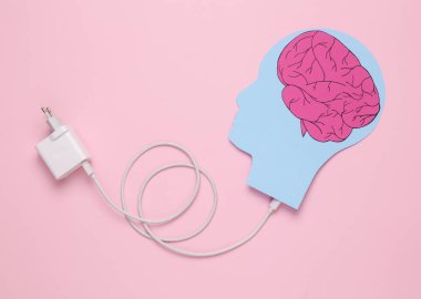Recharge your brains. Paper-cut head with connected charger on pink background