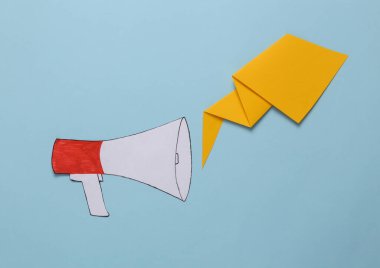 Paper cut cartoon megaphone with dialog cloud on blue background.