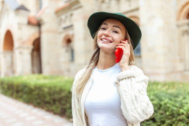 Cute fashion woman in felt hat talking on phone in the city