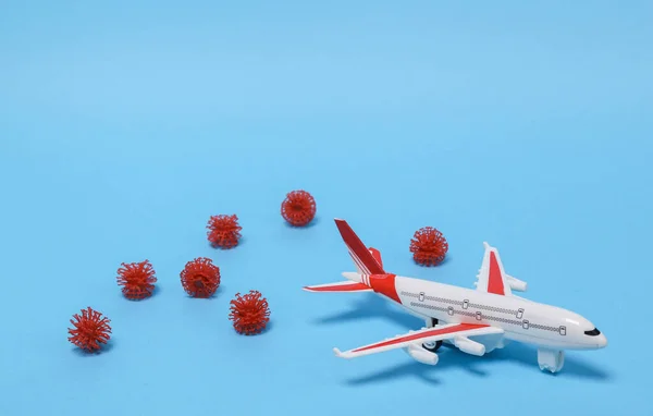The concept of travel during a pandemic. Airplane model with virus strain molecule on blue background