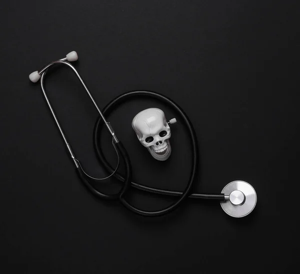 Medical still life. Stethoscope with a skull on a black background. Deadly diseases. Top view