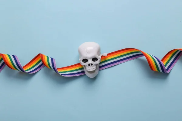 Skeleton head with lgbt rainbow ribbon on a blue background. Concept pop