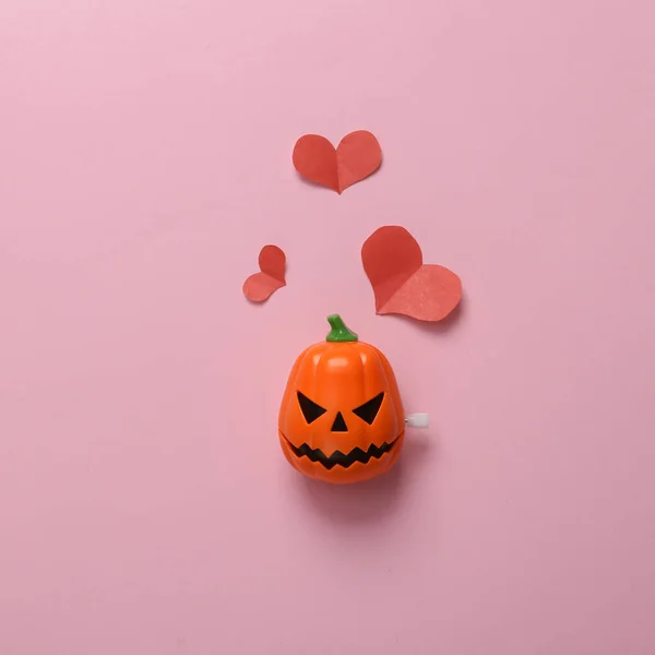 Pumpkin jack head with hearts on a pink background. Valentine\'s day or halloween celebration concept. Minmal layout