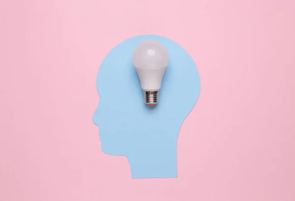 Cutted human head with a light bulb on pink background. Idea concept