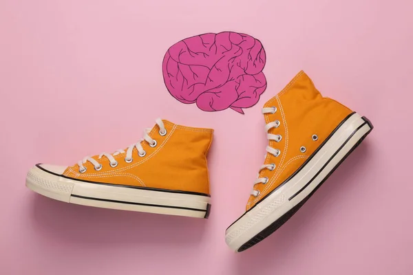 Paper-cut brain and sneakers on a pink background. Flat lay