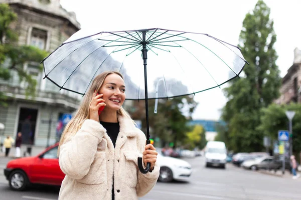 Smiling Fashion Blonde Woman Transparent Umbrella Talking Phone City Lifestyle — Stockfoto