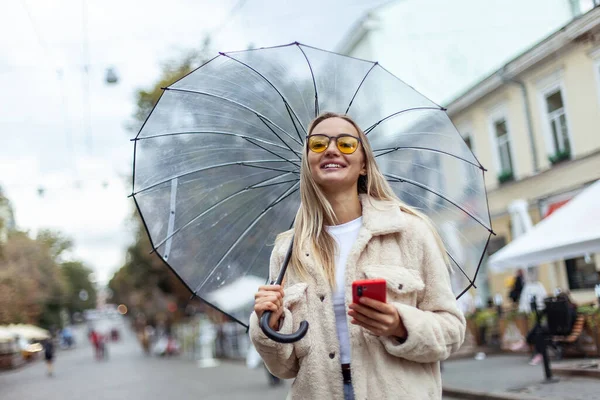 Cute Fashion Blonde Woman Yellow Sunglasses Transparent Umbrella Using Phone — Stockfoto