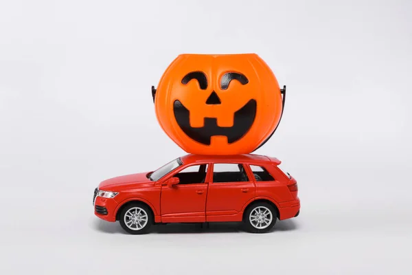 Little car model with halloween jack pumpkin bucket isolated on white background. Trick or Treat