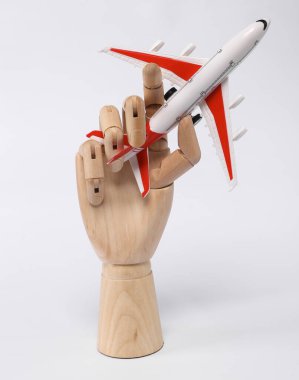 Wooden hand holding airplane model isolated on white background