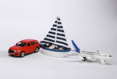 Small model car with passenger plane and sailboat isolated on white background. Travel concept, transport
