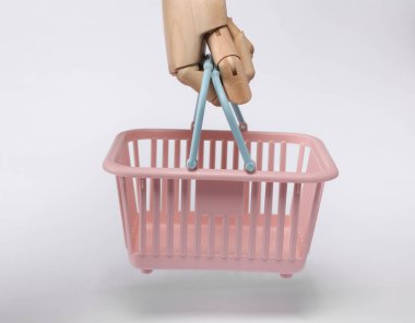 Wooden hand holding Plastic supermarket basket isolated on white background