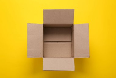 Sarı arkaplanda boş karton kutuyu aç. Üst görünüm