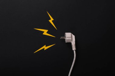 Kısa devre tehlikesi. Siyah arkaplanda kağıttan kesilmiş kıvılcımlar olan elektrik prizi