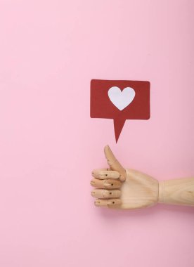 Tahta elli, baş parmaklı ve pembe arka planda uyarı simgesi gibi bir şey. Sosyal medya. Beğeni, takipçiler geri bildirim