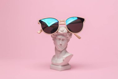 David 'in pembe arka planda güneş gözlüklü büstü. Minimum moda hala hayat. Eski kültür, modern tarz.