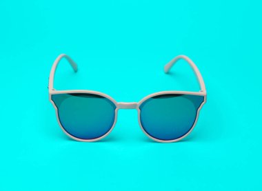 Parlak turkuaz arka planda modaya uygun güneş gözlükleri.