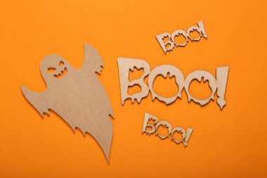 Cadılar bayramı konseptin kutlu olsun. Tahta oyulmuş hayalet ve kelime yuhalaması! turuncu arka planda. Şeker mi şaka mı? Üst görünüm 