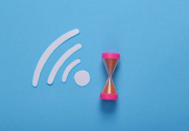 Kağıt mavi arka planda Wi-Fi ikonu ve kum saati kesiyor. Üst görünüm