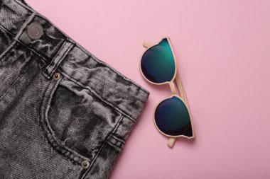 Pembe arka planda güneş gözlüklü kotlar. Üst görünüm