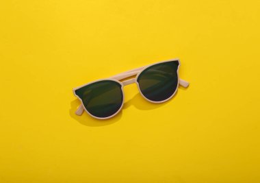 Sarı parlak arkaplanda üstten görünüşlü güneş gözlüğü.