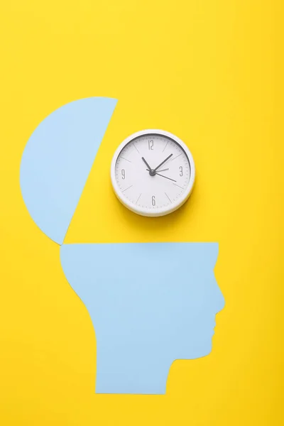 Open your mind, mental health concept, creative thinking. Paper silhouette of human head and clock on yellow background
