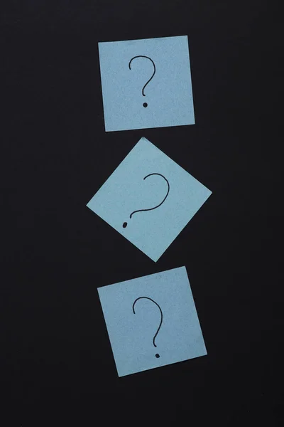 Memo pieces of paper with question marks on black background. Business, psychology, answers to questions concept