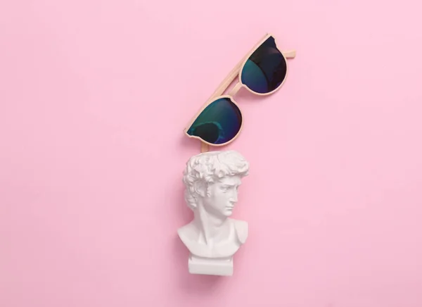 ピンクの背景にサングラスをかけたデビッド バスト 最小限のポップカルチャーのレイアウト トップ表示 — ストック写真
