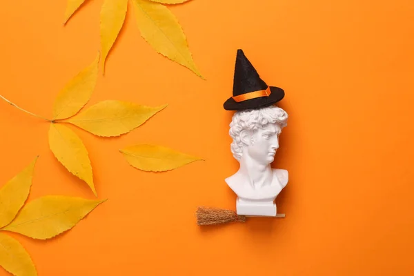 秋の紅葉を背景にオレンジの帽子をかぶった魔女のほうきでデビッドバスト 10月31日幸せなハロウィンのコンセプト最小限のレイアウト — ストック写真