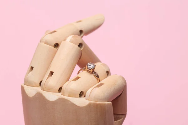 ピンクの背景にダイヤモンドリングと木製マネキンの手 — ストック写真