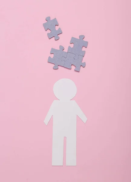 Business, mental health, dementia.  Paper cut man with puzzle pieces on a pink background