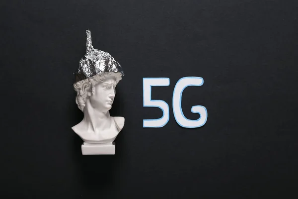 conspiracy theory. David bust in foil hat and word 5G on a black background